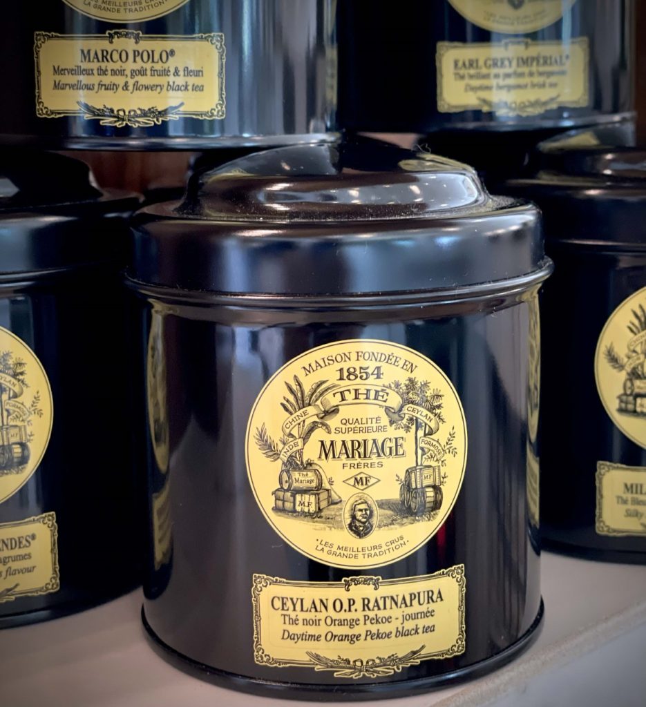 Four tins of tea sitting on a shelf.