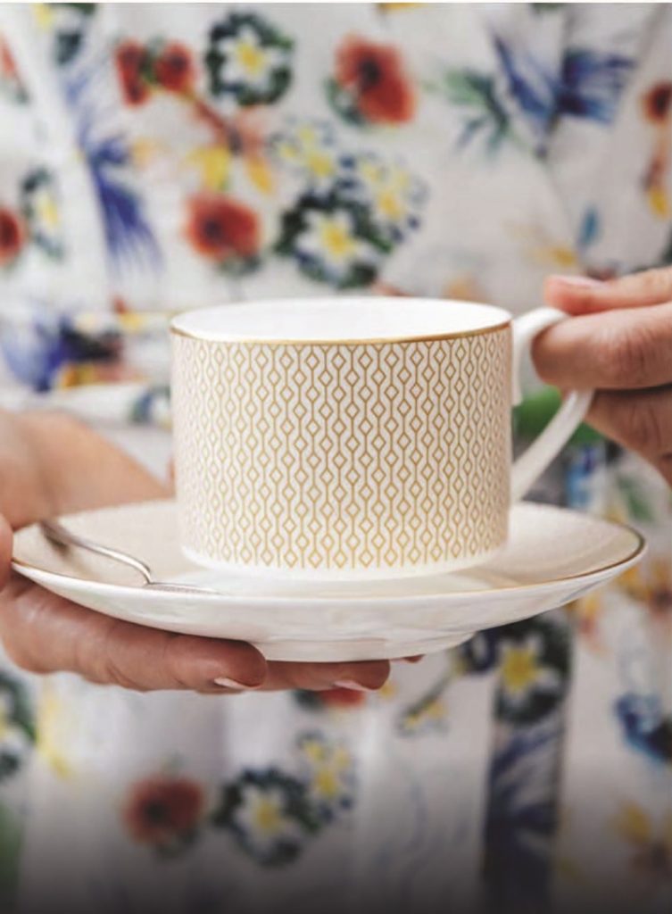 A person holding a cup and saucer.