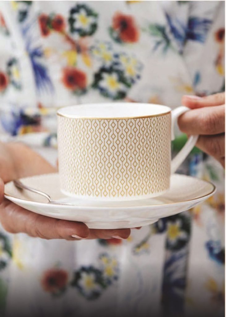 A woman holding a tea cup and saucer.