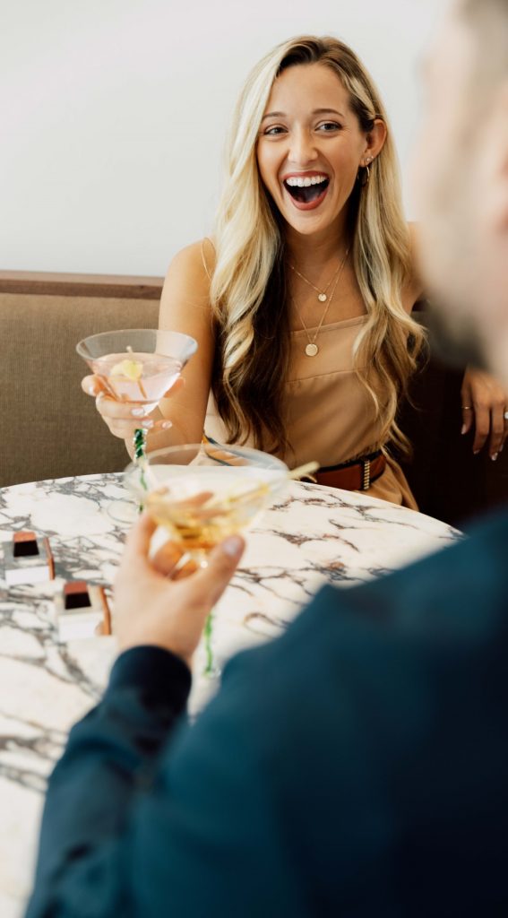 A woman holding a martini glass with her tongue out.