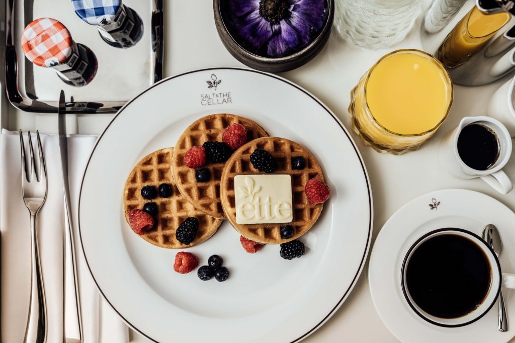 A plate of waffles with berries and butter on a white plate.