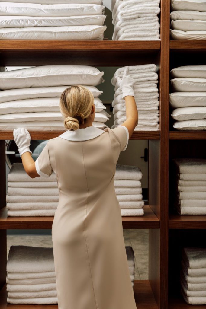 A woman in white dress and gloves working on shelves.