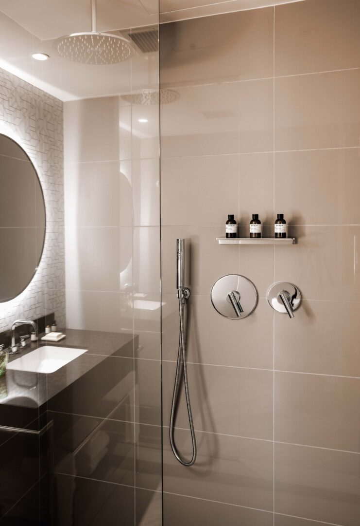 A bathroom with a mirror, sink and shower.