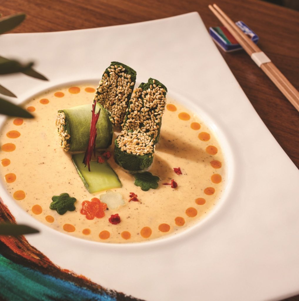 A white plate with a bowl of soup and chopsticks.