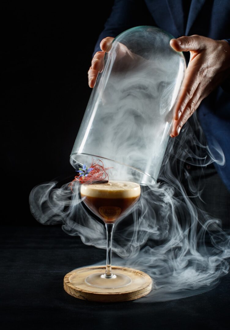 A person pouring liquid into a glass with smoke coming out of the bottom.