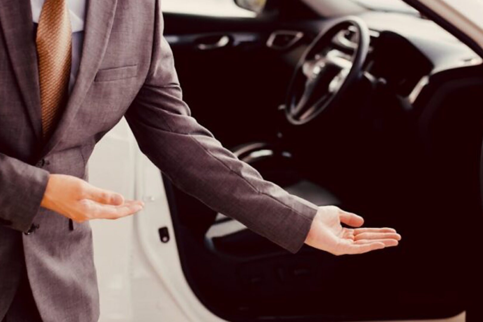 A man in a suit is reaching out of the car
