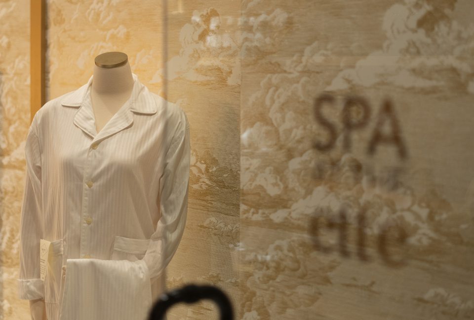 A mannequin wearing white clothes in front of a wall.