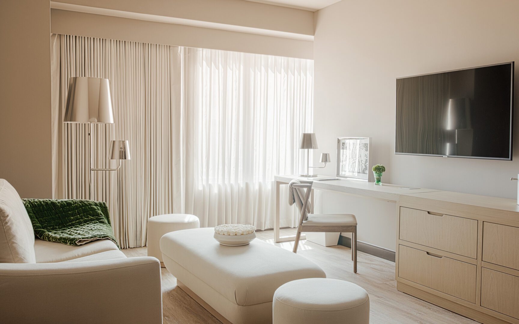 A living room with white furniture and a large window.