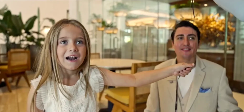 A girl pointing out to a man inside a house