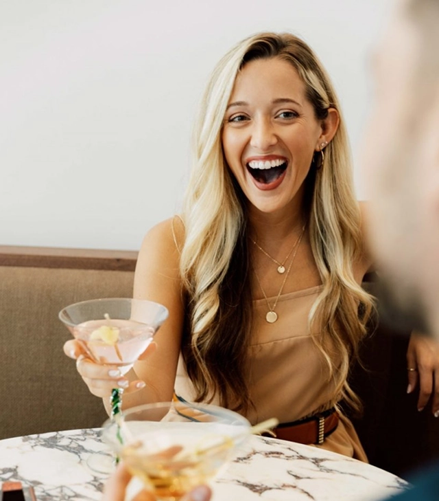 Smiling guest holding a cocktail at a table